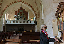 Die Vorsitzende des Fördervereins Stefanie von Laer am Richborn-Positiv im Altarraum der Dorfkirche Ruchow, im Hintergrund auf der Empore die fast fertiggestellte Paul-Schmidt-Orgel