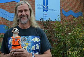 Fred, Maskottchen der Weltmeere, besucht Hamburg. Diakon Jan Oltmanns vom Seemannsclub "Duckdalben" freut sich.