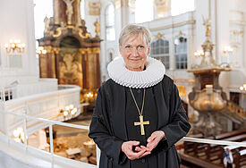 Bischöfin Kirsten Fehrs steht in Ornat und mit Bischofskreuz auf einer Empore der Hamburger Hauptkirche St. Michaelis