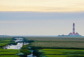 Der Leuchtturm Westerheversand in Nordfriesland liegt umgeben von der umliegenden Salzwiesenlandschaft an der Nordseeküste. 