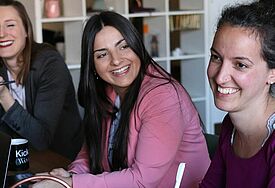 Frauen sitzen und lachen an einem Tisch