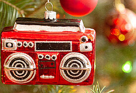 Ein Anhänger in Form eines Radios hängt an einem festlich geschmückten Weihnachtsbaum.