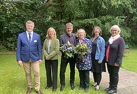 Sechs Personen stehen nebeneinander auf einer grünen Rasenfläche. Im Hintergrund stehen Bäume im vollen Laub. Die Personen von links nach rechts sind Synodenpräses Professor Dr. Stefan Krüger, Nora Steen, Bischöfin des Sprengels Schleswig und Holstein, Mathias Lenz, Inken Wöhlbrand, Dr. Christine Weide und die stellvertretenden Synodenpräses Heinke Mahrt.