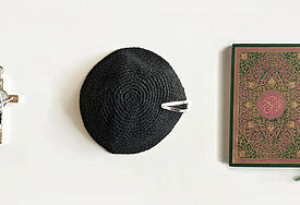 Symbole für die drei monotheistischen Weltreligionen Christentum, Judentum und Islam: Kreuz, Kipa und Koran