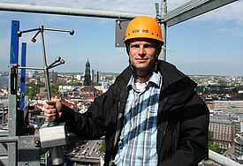 Woher weht der Wind? Meteorologe Ingo Lange präsentiert das Ultraschall-Gerät über den Dächern von Hamburg