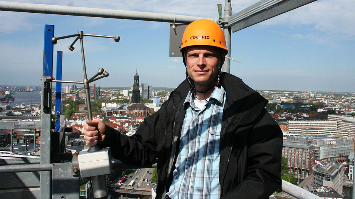 Woher weht der Wind? Meteorologe Ingo Lange präsentiert das Ultraschall-Gerät über den Dächern von Hamburg