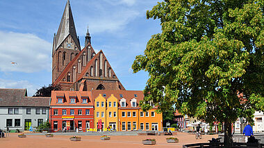 Der Markt mit der St. Marienkirche im nordvorpommerschen Barth. Bunte Häuser stehen vor dem Kirchbau.