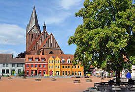 Der Markt mit der St. Marienkirche im nordvorpommerschen Barth. Bunte Häuser stehen vor dem Kirchbau.