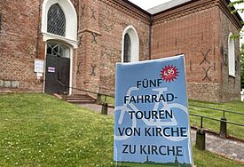 Nahaufnahme Infoflyer mit Aufschrift von Kirche zu Kirche vor Kirchenmauer