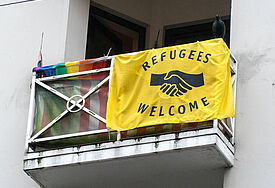"Refugees welcome"-Flagge mit Regenbogenfahne 