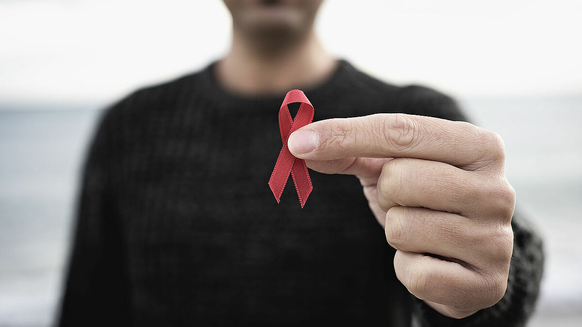 Die rote Schleife sagt: Ich zeige mich solidarisch mit HIV-Positiven. Am 1. Dezember wird sie vielerorts sichtbar sein, um dafür zu werben, dass jeder Mensch Zugang zu Präventions- und Behandlungsmöglichkeiten haben sollte  – unabhängig von Geschlecht, sexueller Orientierung und Herkunft. 