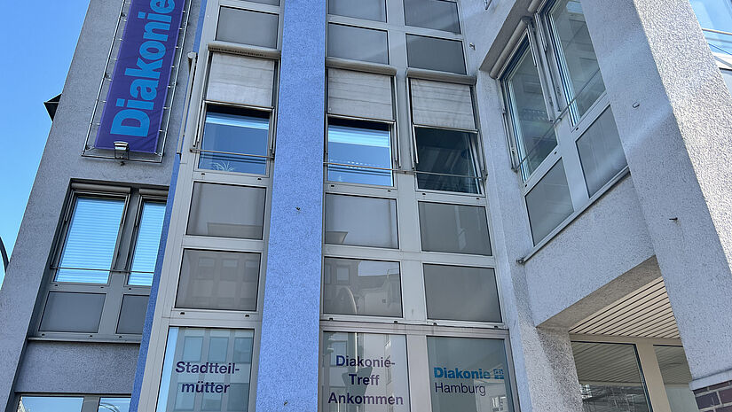 Immer donnerstags wird hier in der Königstraße Second-Hand-Spielzeug und Kinderkleidung kostenlos an Bedürftige abgegeben. Ein Büro- und Ladengebäude in der der Königstraße. Im Fenster steht Stadtteilmütter.