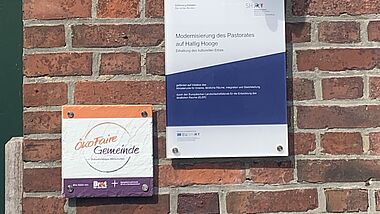 Schild "ÖkoFaire" Gemeinde an einer Kirche auf Hallig Hooge