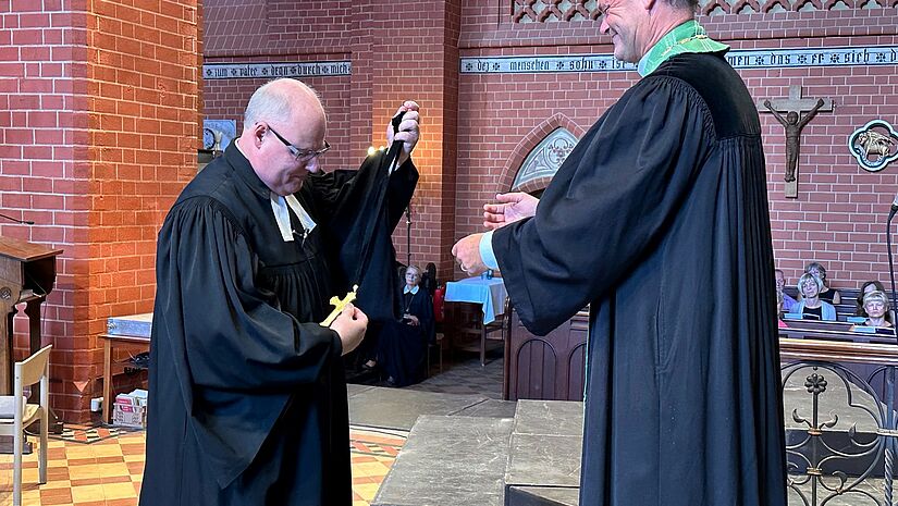 Propst Dirk Sauermann (l.) übergibt sein Amtskreuz an Bischof Tilman Jeremias.