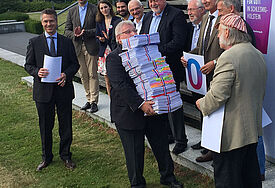 Bis zur Nasenspitze von Landtagspräsident Klaus Schlie reichte das Bündel an Unterschriften, das ihm am 14. Juli 2015 von einer Abordnung der Volksinitiative Gottesbezug übergeben wurde