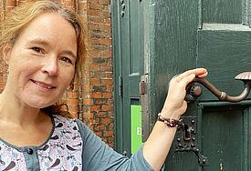 "Wir wollen mit unserem Gottesdienst zur Hospiz- und Palliativwoche Türen öffnen", sagt Pastorin Mareike Hansen. Sie steht dabei vor einer halb geöffneten großen grünen Kirchentür und hält die metallene Klinke in der Hand.
