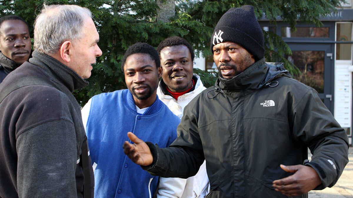 Fluchtlinge WEB Flüchtlinge aus Afrika: Zakaria Shahadu (2.v.l.), Kwame Damiel (3.v.l.), und Ismail Alhassan mit einem Passanten