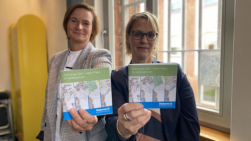 Von links nach rechts: Gesa Kitschke (Diakonie Altholstein) und Yvonne Radetzki (Leiterin der JVA Neumünster) präsentieren das Buch "Wenn Papa im Gefängnis ist". 