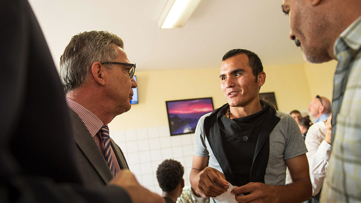 Innenminister Thomas de Maizière im Gespräch mit Flüchtlingen in der Erstaufnahmeeinrichtung Brandenburgs
