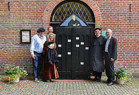 Pastor Roland Scheel (Kirchengemeinde Warder), Laura Grimm (als Katharina von Bora), Peter Wiegner (Präses der Kirchenkreissynode), Pastor Karsten Baden-Rühlmann (als Martin Luther, Bildungswerk) und Pastor Ekkehard Wulf (stv. Propst des Kirchenkreises Plön-Segeberg und Kirchengemeinde Nahe) an der Thesentür.