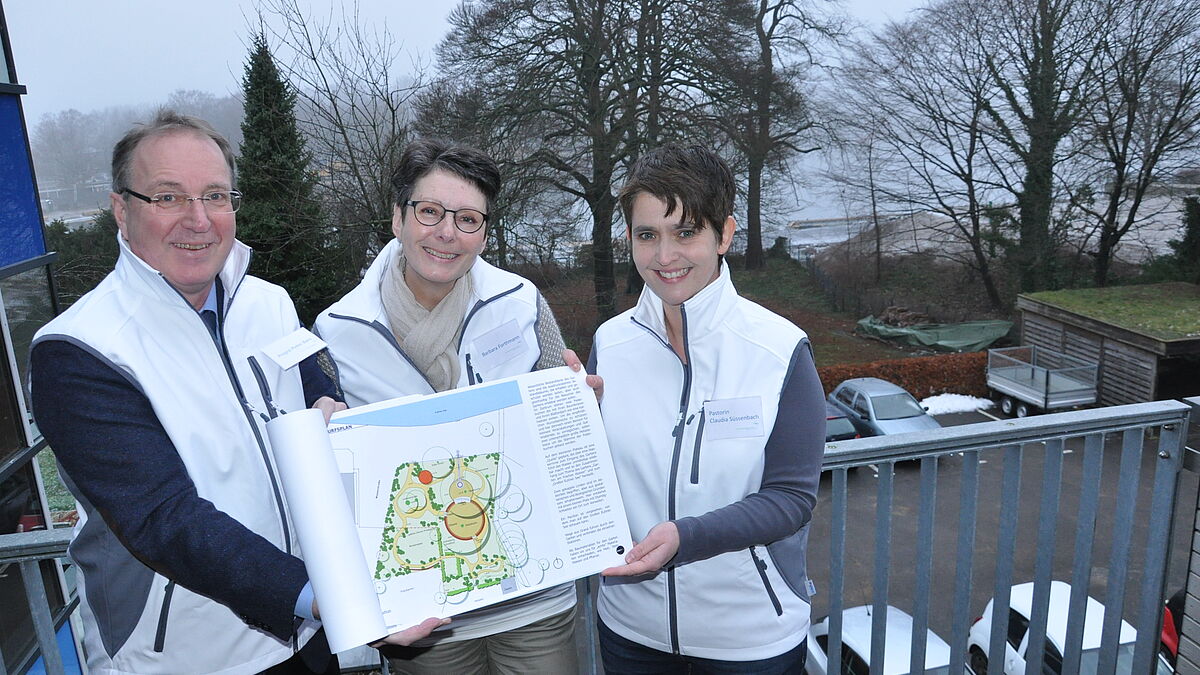 Propst Peter Barz (v.l.), Barbara Forthmann und LGS-Pastorin Dr. Claudia Süssenbach mit den Plänen für den Garten am frischen Wasser 