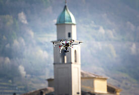 Eine Kameradrohne schwebt vor einem Kirchturm in Italien