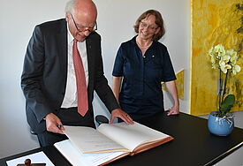 Der Landesbischof steht an einem Schreibtisch und blättert im Goldenen Buch