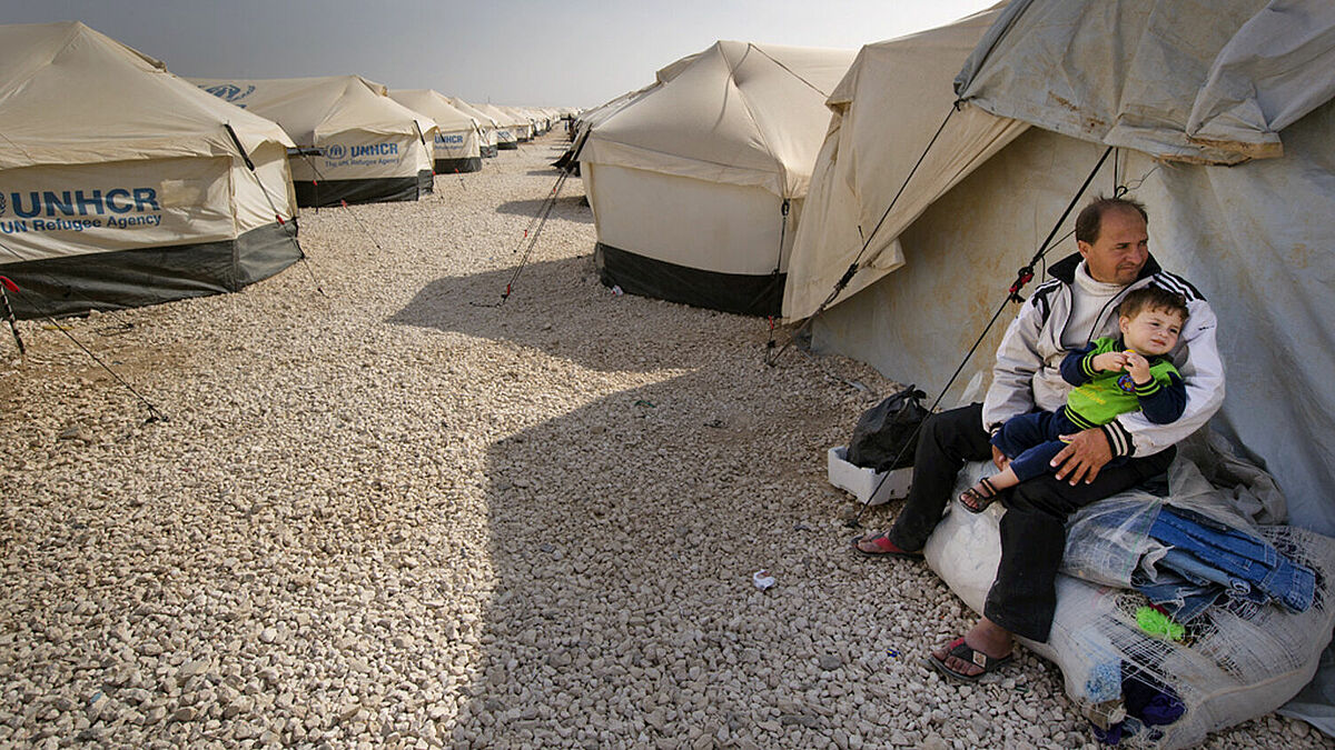 Syrische Flüchtlinge warten in einem Flüchtlingscamp darauf, dass ihnen ein Zeltplatz zugewiesen wird.
