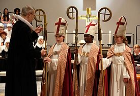 Hauptpastor Martin Vetter legt Christian Kratzsch (11), Raphael Owuso Opuko (10) und Mila Jandt (10) das Bischofskreuz um (von links)