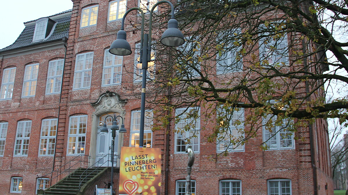 Vor dem historischen Drostei-Gebäude aber auch an vielen anderen Orten der Innenstadt hängen Plakate mit dem Aufruf "Lasst Pinneberg leuchten!". Die Aktion soll Bürgern und Geschäftsleuten Zuversicht in der Corona-Krise geben. 