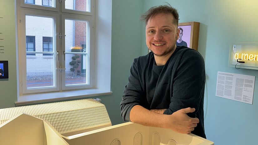 Der Museumsleiter Jonas Kuhn steht in einem Raum an einem Modell des Museumsgebäudes 