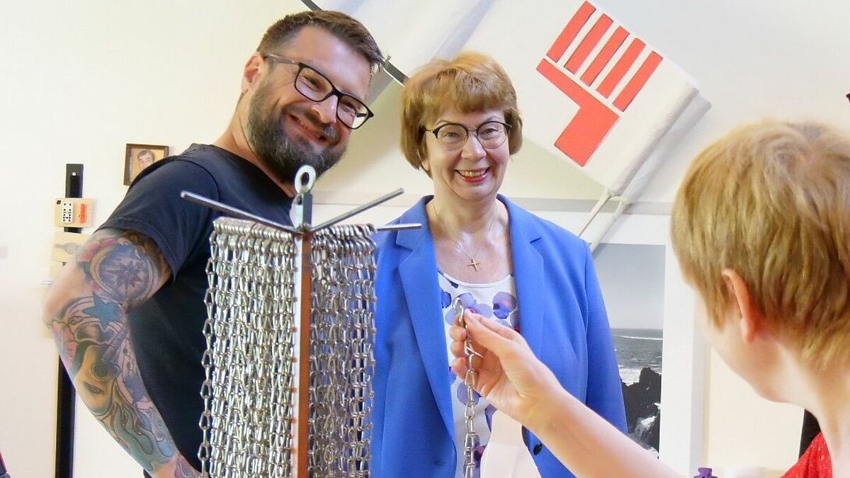 Landesbischöfin Kühnbaum-Schmidt (m) im Gespräch mit dem Teamleiter der Tagesförderstätte der Schleswiger Werkstätten Dirk Ehmke (li) und einer Werkstattbeschäftigten