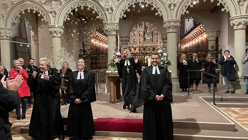 Ordination mit Glitzer und Gloria im Schleswiger Dom: Bischöfin Nora Steen freut sich mit den drei Ordinierten. Gold-Glitzer regnet auf die frisch Ordinieren im Schleswiger Dom herunter. Die neuen Pastorinnen, der neue Pastor und Bischöfin Steen lachen ausgelassen.