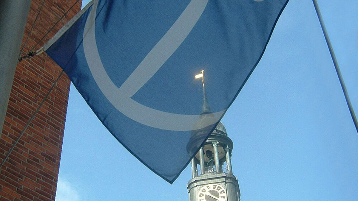 Flagge des Seemannsheims weht im Wind, dahinter sieht man die Spitze des Michels