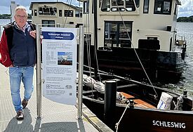 Pastor Michael Bruhn neben dem Jesusboot im Schleswiger Hafen.