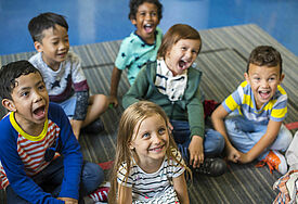 Kinder sitzen auf dem Boden und singen