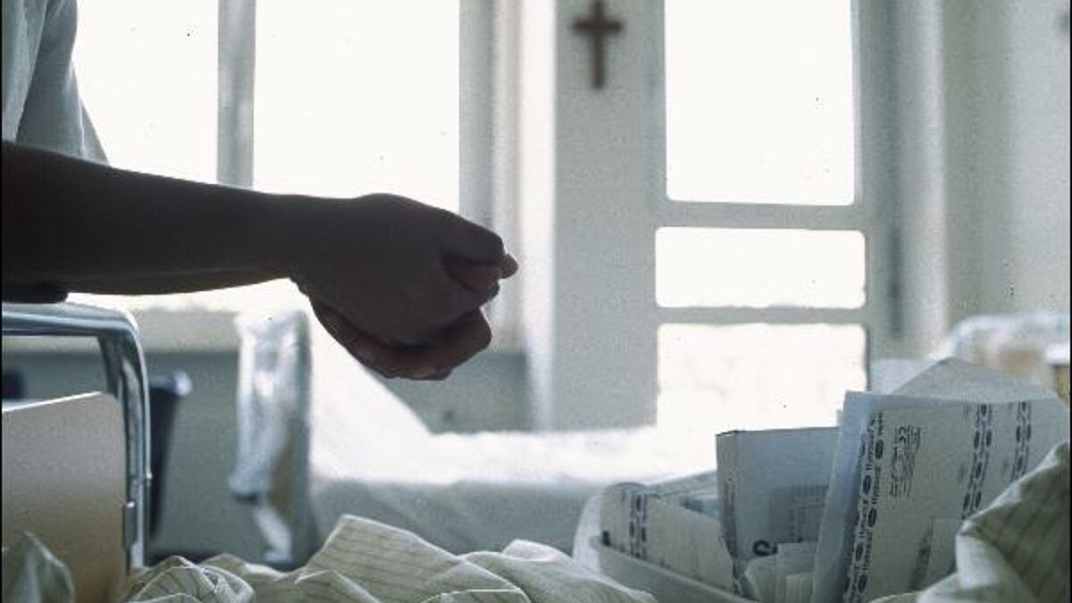 Ein Seelsorger sitzt am Bett eines Patienten. (Symbolbild)