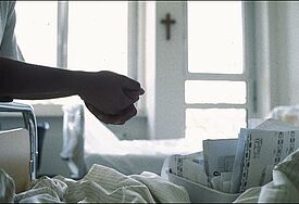 Ein Seelsorger sitzt am Bett eines Patienten. (Symbolbild)
