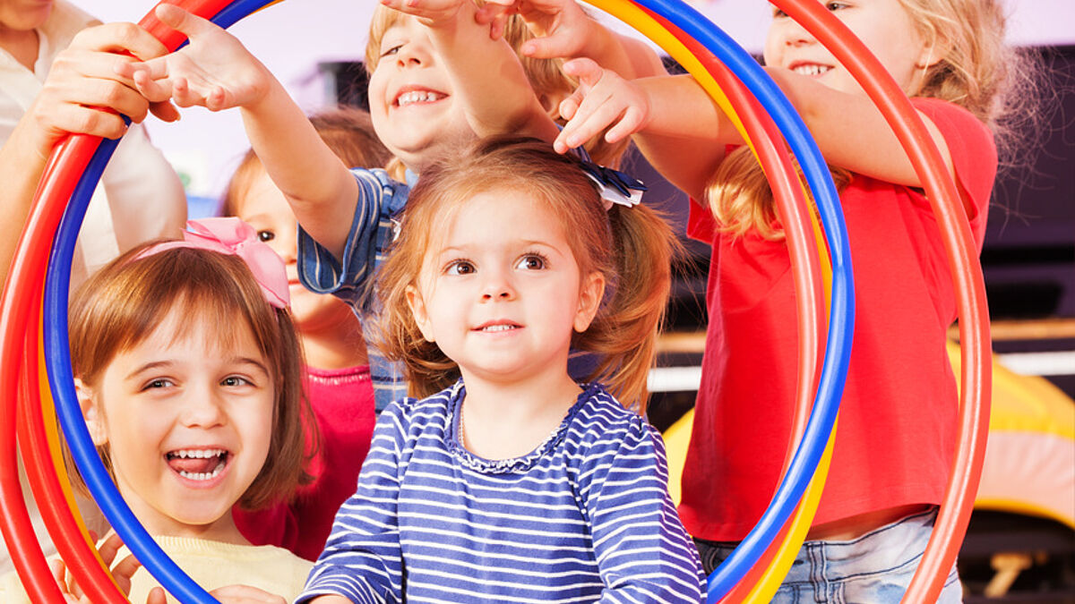 Many happy kids boys and girls look through plastic sport hop stretching hands
