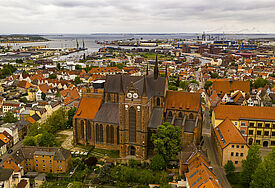 Luftaufnahme der St.-Georgen-Kirche in Wismar. Im Hintergrund ist der Hafen und die Ostsee zu sehen.
