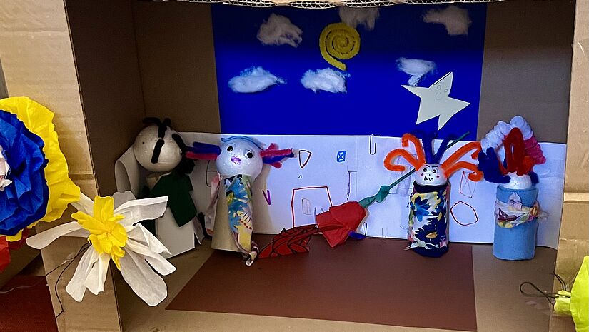 Bastelarbeit aus dem Kindergottesdienst der Poeler Kirche Aus Styropor und Stoffresten haben Kinder Figuren gebastelt, die in einem Karton stehen, so dass es wie eine Theaterbühne wirkt. An die Kanten des Kartons sind Blüten aus Krepp geklebt.