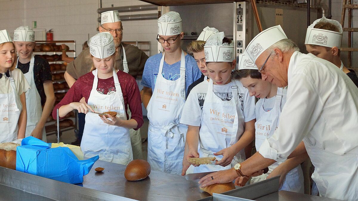 Wie die frisch gebackenen Brote wohl schmecken? Landesbischof Gerhard Ulrich (r.) und die Konfirmandinnen und Konfirmanden aus Rostock-Schmarl/Groß Klein und Lambrechtshagen probierten es gleich aus.