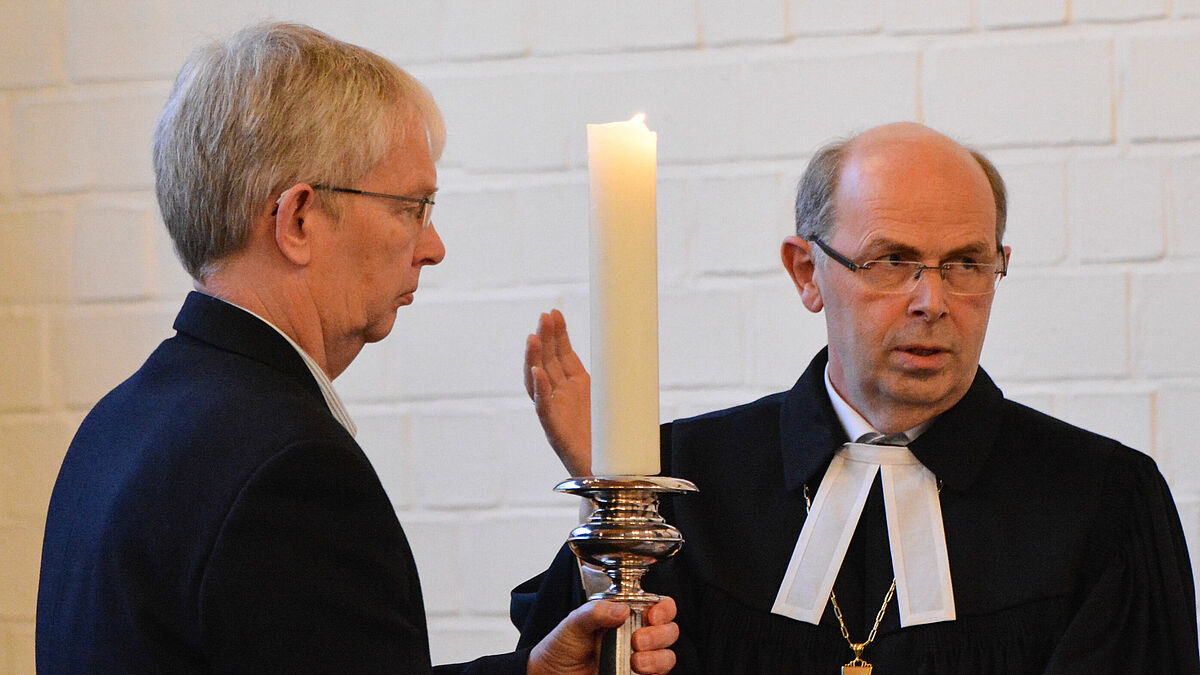 Bischof Gothart Magaard übergibt in St. Michaelis Süd (Schleswig) die Kerze an an Henning Lüthke, Präses der Kirchenkreissynode des Kirchenkreises Schleswig-Flensburg.