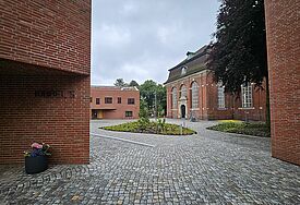 Blick durch Neubauten auf einen Innenhof. Die Gebäude sind in roter Backsteinoptik gebaut. 