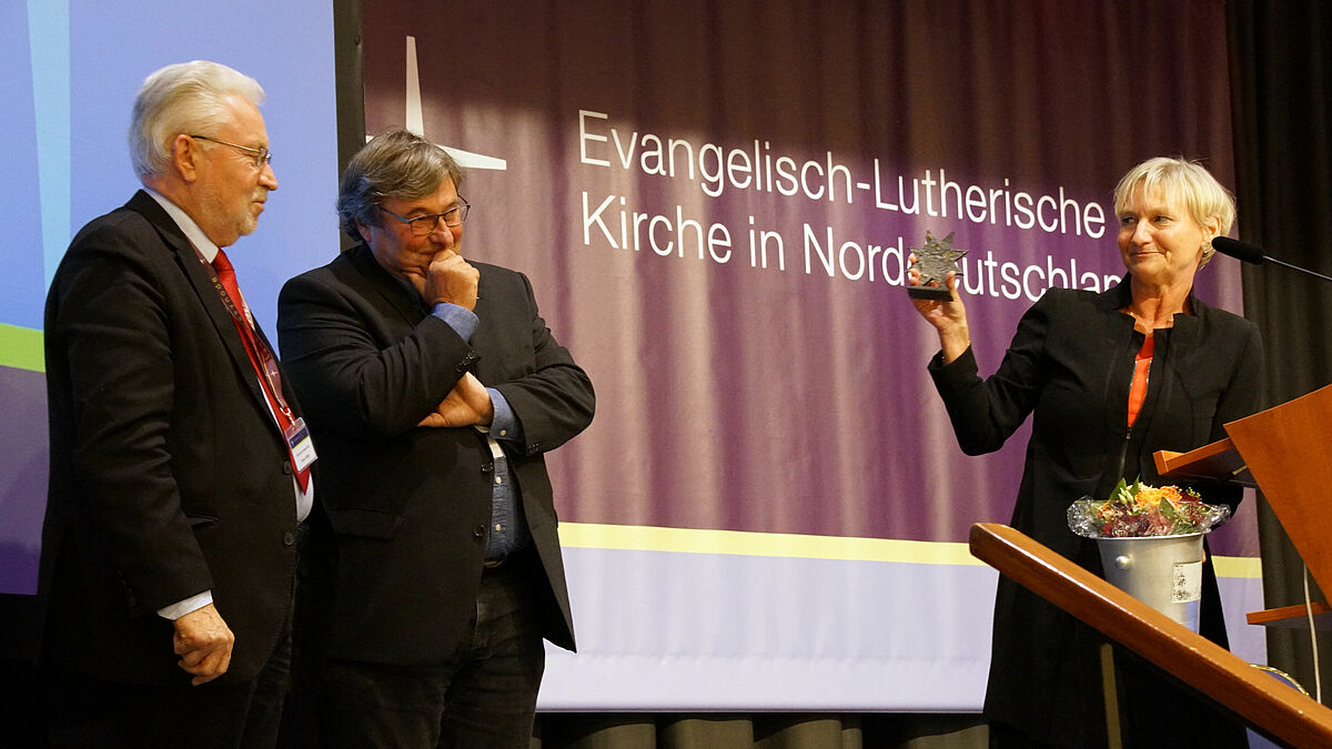 Bischöfin Kirsten Fehrs dankte Claus Möller (l.) für sein jahrzehntelanges Engagement als Finanzausschussvorsitzender mit dem "Nordstern". Dr. Ralf Büchner (Mitte) hatte den Synodalen zuvor den Haushalt 2019 vorgestellt