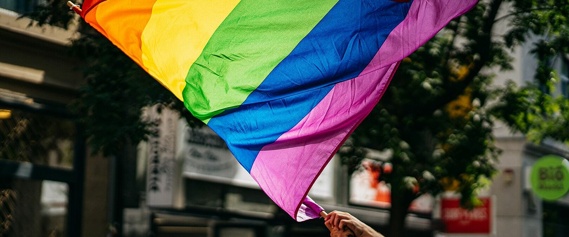 Hand, die eine Regenbogenflagge auf der Straße schwenkt
