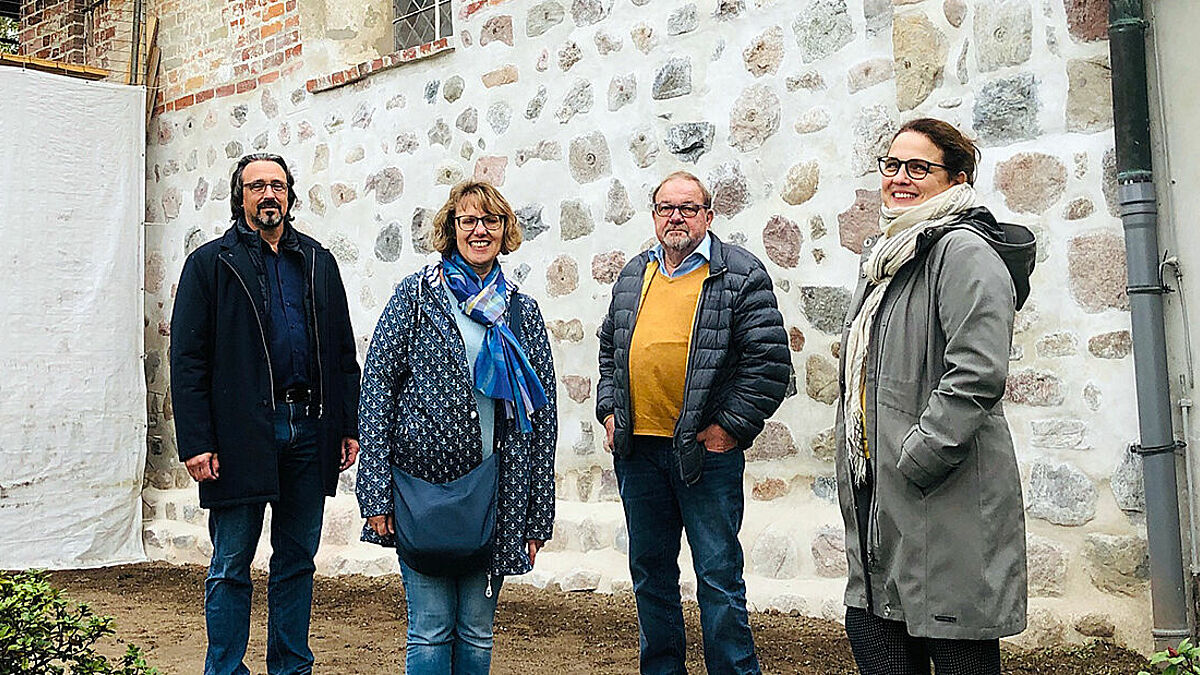 Mark-Oliver Kraft, Mitglied des Kirchengemeinderates, Pastorin Britta Sandler, Rüdiger Jarchow, stellvertretender Kirchengemeinderats-Vorsitzender und Liane Kreuzer, Leiterin der Bauabteilung des Kirchenkreises Lübeck-Lauenburg, vor der fertig sanierten Mauer an der Ostseite der Kirche. 