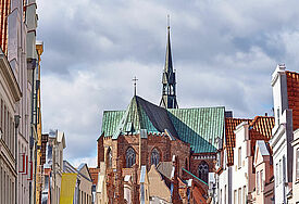 Die Glockengießerstraße ist mit bunten Wimpeln geschmückt. Die Katharinenkirche am Ende der Straße hat ein grünes Kupferdach.
