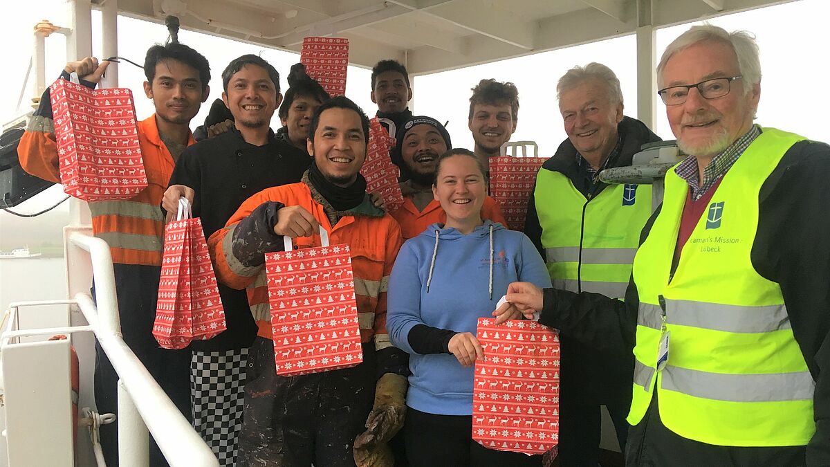 Hans Hartke (v.re.) und Henning Wulff von der Deutschen Seemannsmission in Lübeck bringen Kapitänin Vicky Neumann und der Crew der "Vanquish" Weihnachtsgeschenke.