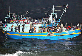 Ein mit etwa 500 Flüchtlingen überladenes Boot aus Libyen läuft nachts vor Lampedusa auf Grund (Mai 2011). Mit Booten wie diesem sind auch die in Hamburg gestrandeten Flüchtlinge über das Mittelmeer nach Italien geflohen.
